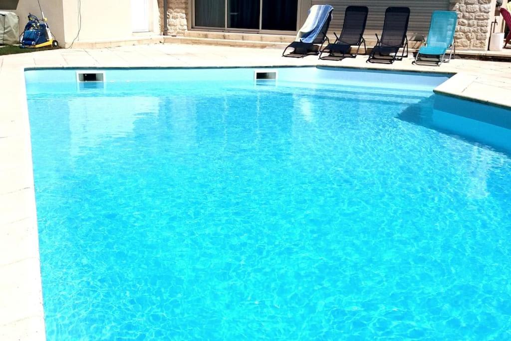 a large blue swimming pool with chairs in it at Gîte du Midi de Saint-Porchaire - Charmante maison de vacances avec piscine chauffée in Saint-Porchaire