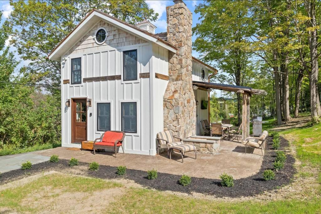 a small white cottage with a stone chimney at Cozy Two Bedroom Home On Canandaigua Lake in Rushville