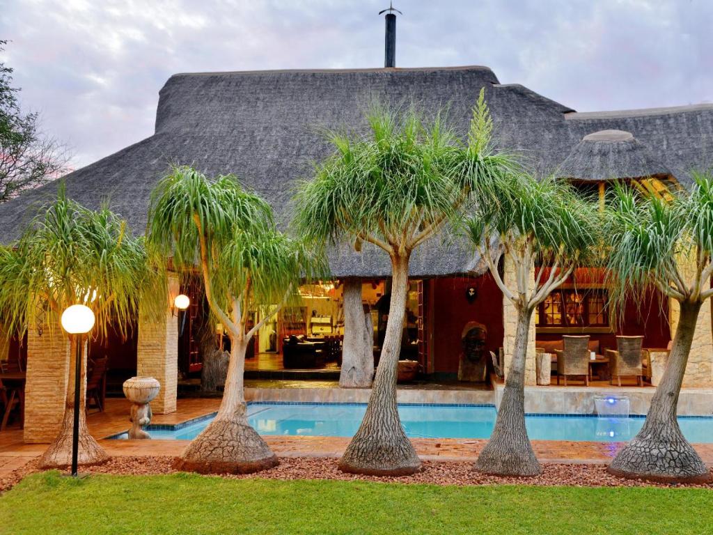 a group of palm trees in front of a house at Winterfell Lephalale Lodge in Lephalale