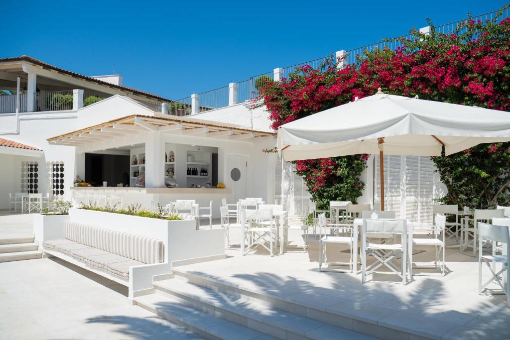 a patio with white chairs and tables and umbrellas at Ostuni a Mare in Ostuni