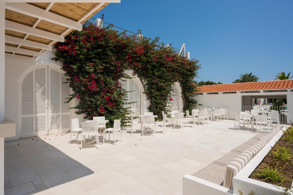 an outdoor patio with white chairs and red flowers at Ostuni a Mare in Ostuni