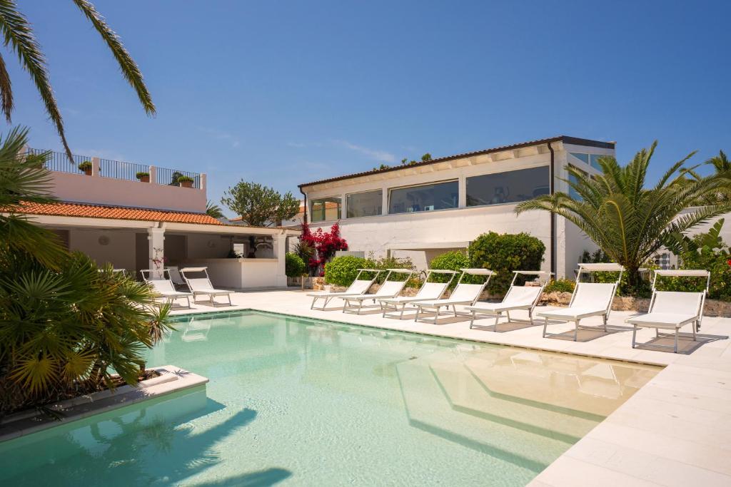 a swimming pool with chairs and a house at Ostuni a Mare in Ostuni