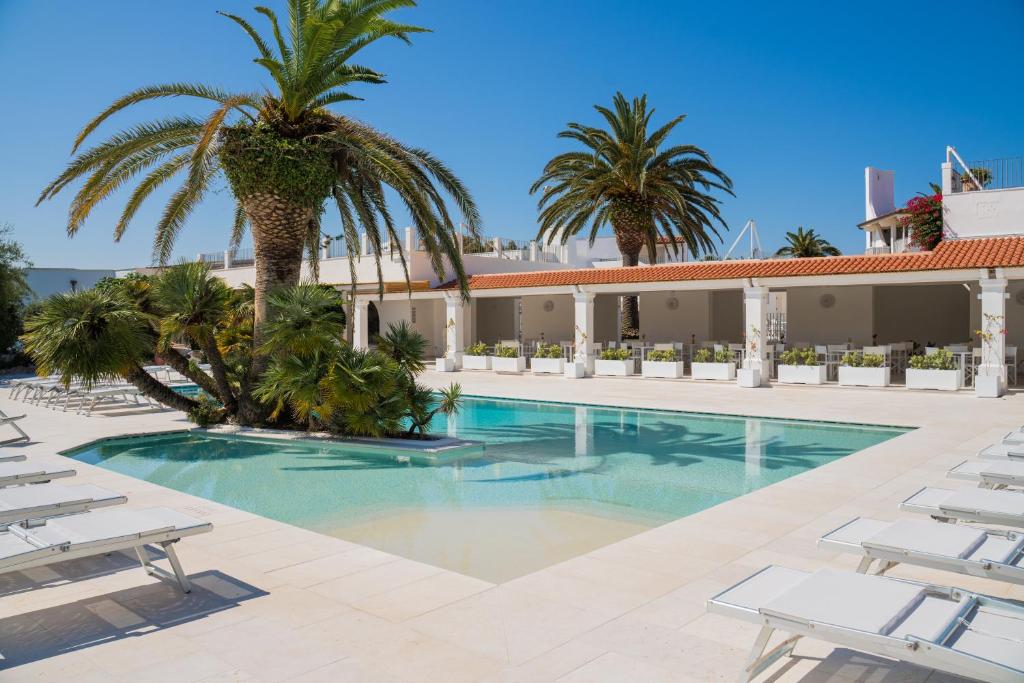 a swimming pool with palm trees and lounge chairs at Ostuni a Mare in Ostuni
