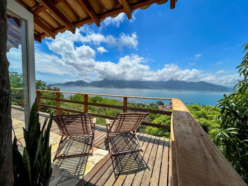two chairs on a deck with a view of the ocean at Chalé com vista para o mar in Ilhabela