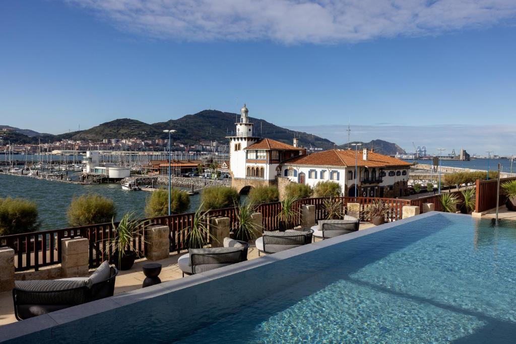 a swimming pool on top of a building with a view of the water at Palacio Arriluce Hotel in Getxo