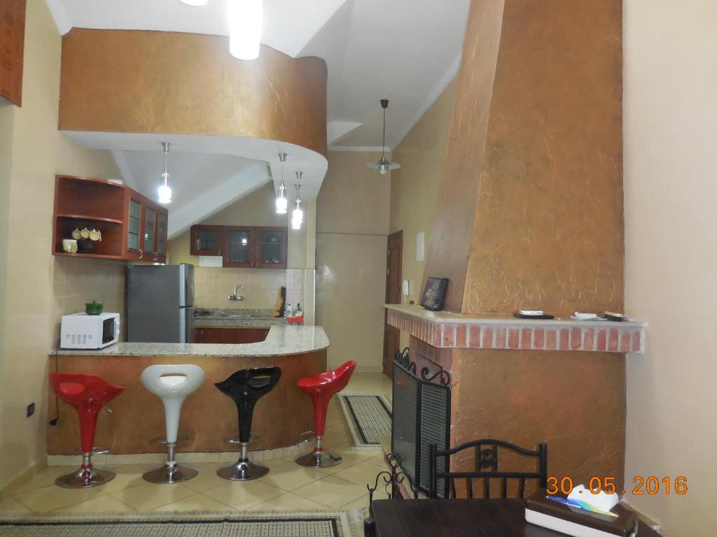 uma cozinha com um balcão e bancos vermelhos num quarto em Bel Appartement à Ifrane em Ifrane