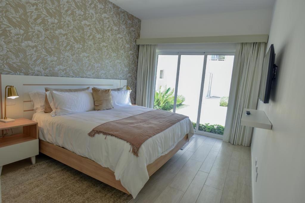 ein Schlafzimmer mit einem großen Bett und einer Glasschiebetür in der Unterkunft Hard Rock at Cana Pearl by Unwind Properties in Punta Cana