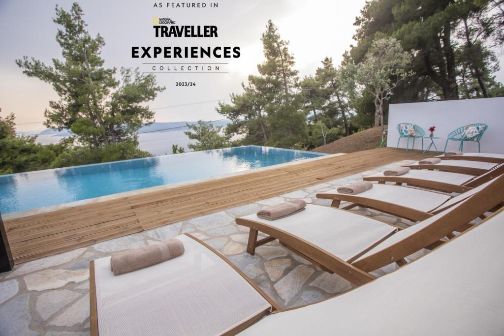 a group of lounge chairs and a pool at Allure Luxury Villas in Skiathos