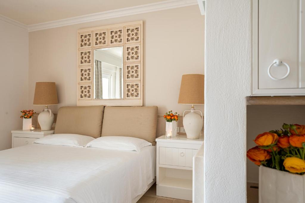 a white bedroom with a bed and a mirror at Ostuni a Mare in Ostuni
