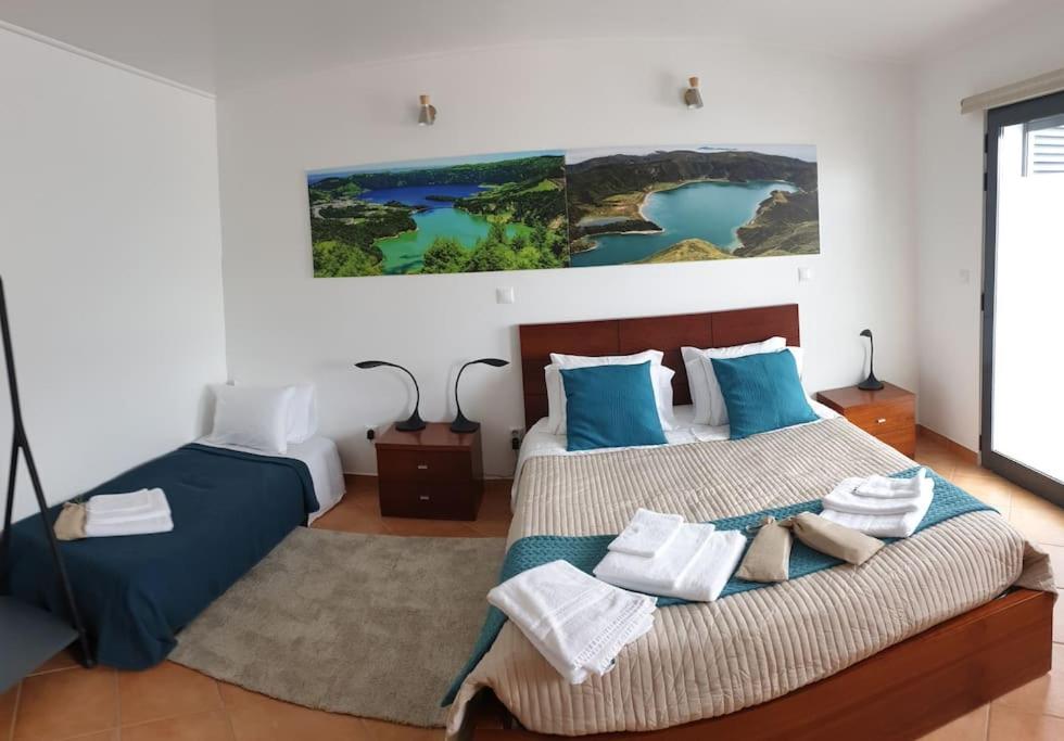um quarto com 2 camas com almofadas azuis e brancas em A Caminho da Ilha em Ponta Delgada