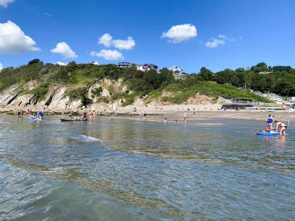 a group of people in the water at a beach at Pet Friendly 2 Bed Coastal Property - Millendreath, Looe in Looe