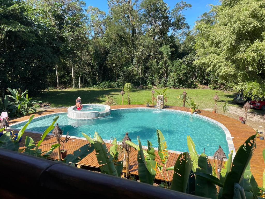 a swimming pool with a fountain in a yard at Bali Suites Itamambuca in Ubatuba