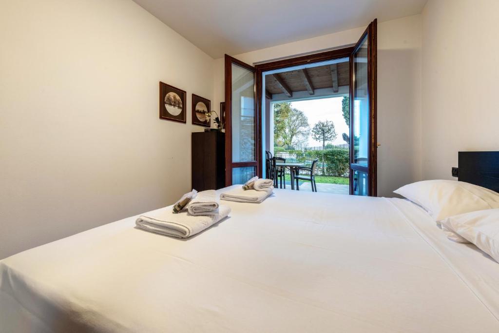 1 dormitorio con 1 cama blanca grande y toallas. en Rosa Flat - with Pool, en Polpenazze del Garda