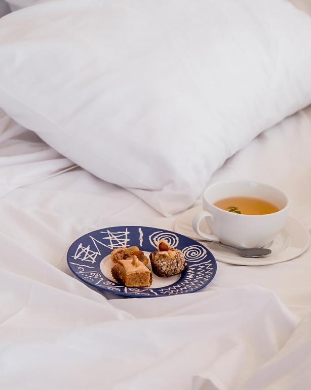 a plate of food and a cup of tea on a bed at Emeraude Camp Agafay in El Karia