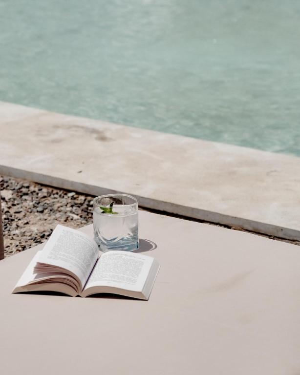 an open book and a glass of water on a table at Emeraude Camp Agafay in El Karia