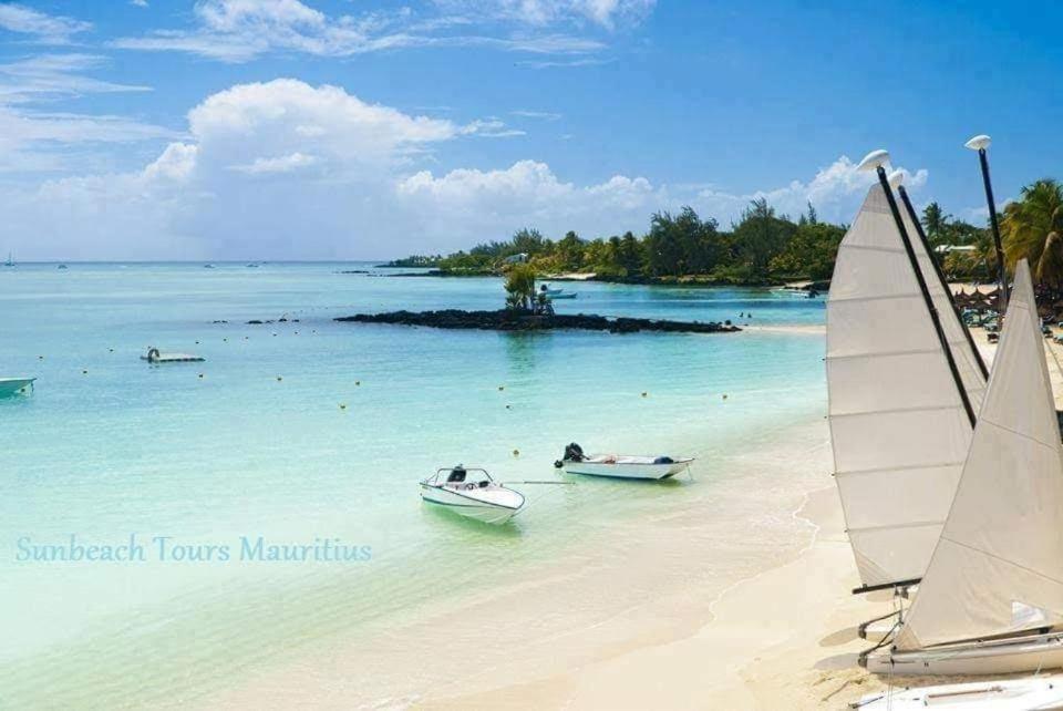 two boats in the water on a beach at MAURISIA APARTMENT Trou Aux Biches in Pamplemousses Village