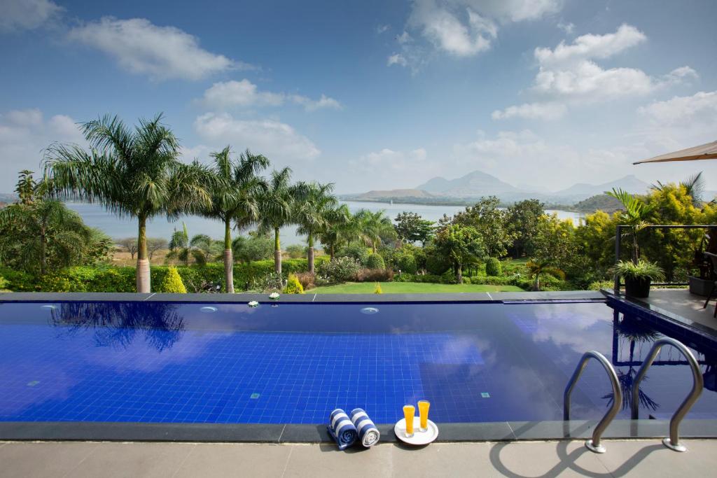 a swimming pool with a view of the ocean at SaffronStays Alandi Waters in Nashik