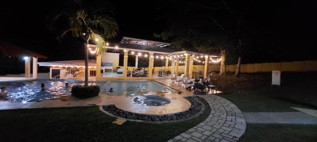 a pool at night with people sitting around a table at Villas Jr estudio 3 by Oasis Guacalillo in Tarcoles