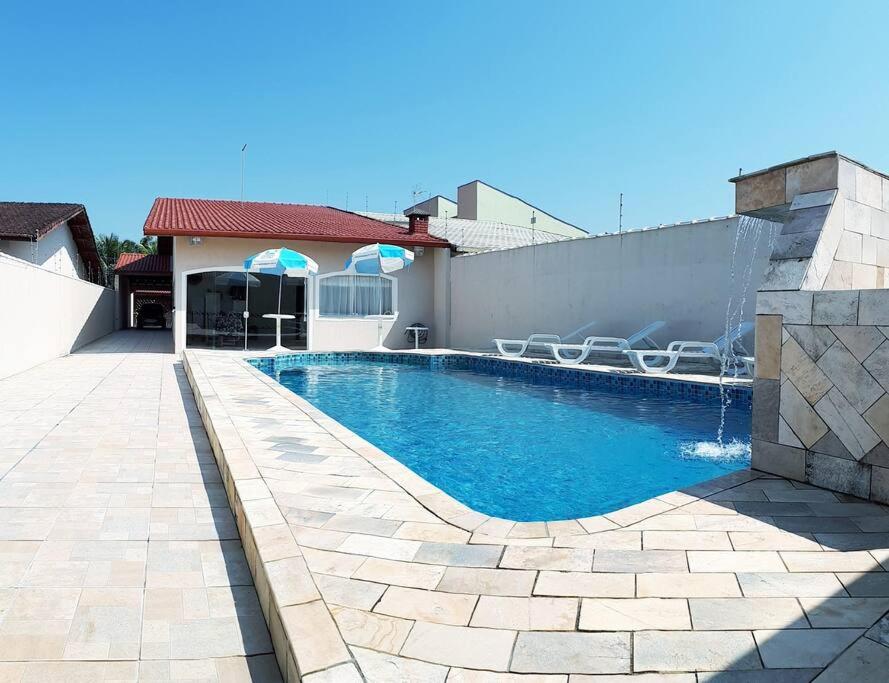 a swimming pool with a fountain in a backyard at Casa confortável com 4 suítes para até 20 pessoas. in Itanhaém