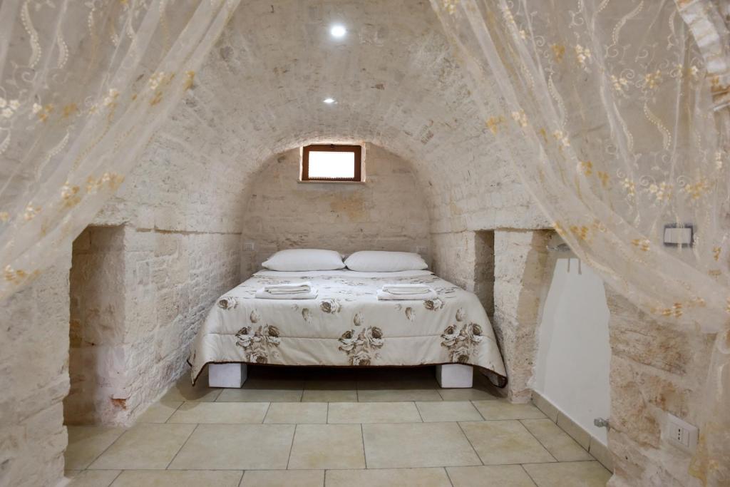 阿爾貝羅貝洛的住宿－Agape fra i Trulli Dimora Orchidea，卧室配有一张石墙床