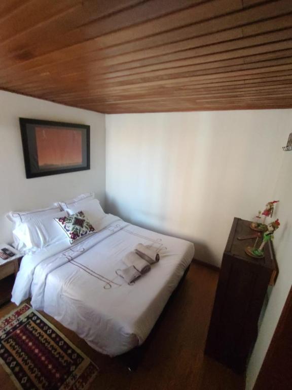 una camera da letto con un letto con lenzuola bianche e un soffitto in legno di Habitación ITCI – Terminal Salitre a Bogotá