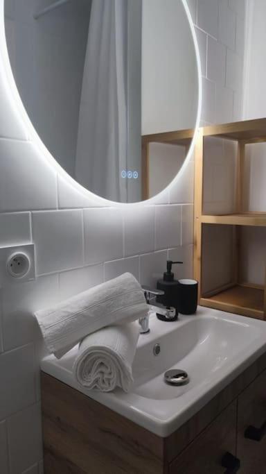 - un lavabo avec miroir et une serviette dans l'établissement Charmant T1Bis rénové avec goût, à Rodez