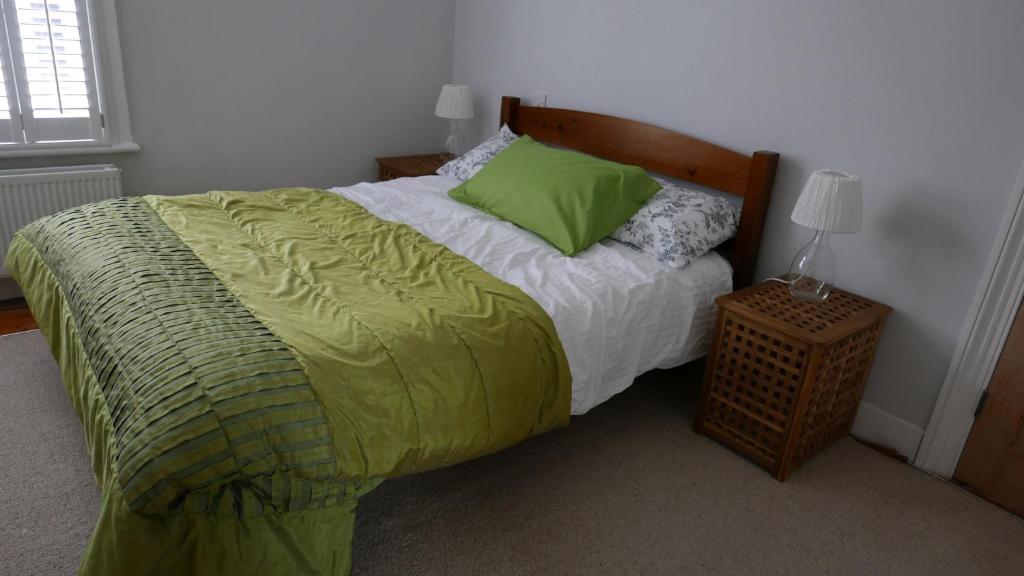 a bedroom with a bed with a green comforter at London 2 Bed Flat Zone2 in London