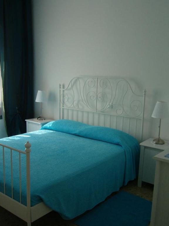 a bedroom with a bed with a blue blanket at Appartamenti Condominio Daniele in Grado