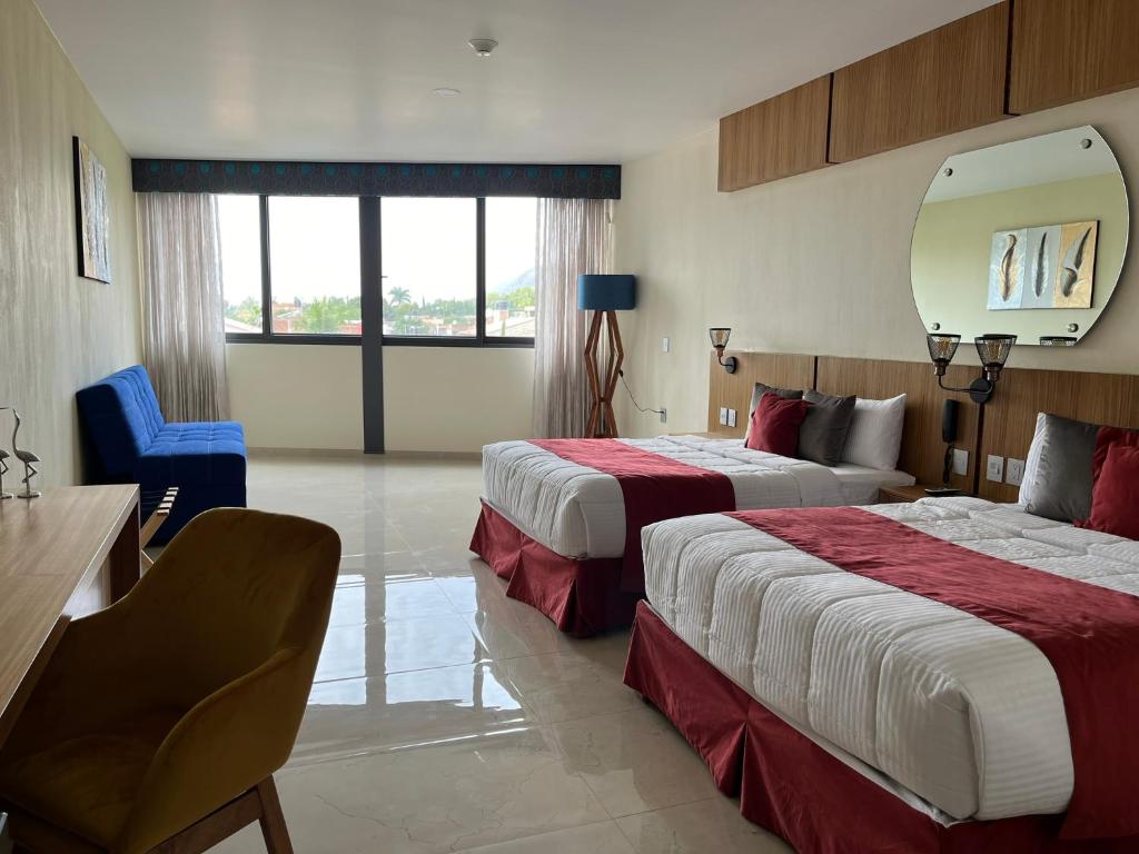 a hotel room with two beds and a mirror at Hotel Cinco Diamantes in Atotonilco el Alto