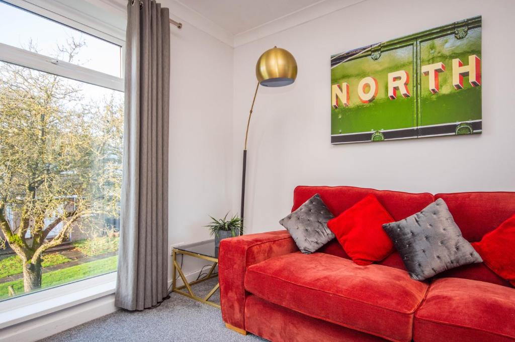 czerwona kanapa w salonie z oknem w obiekcie 2 bed spacious, light & quiet flat, free parking w mieście Heaton