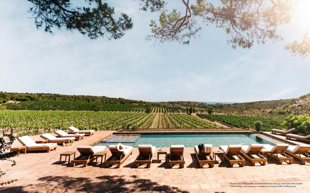 une piscine avec des chaises longues et une vue sur un vignoble dans l'établissement Château L'Hospitalet Wine Resort Beach & Spa, à Narbonne