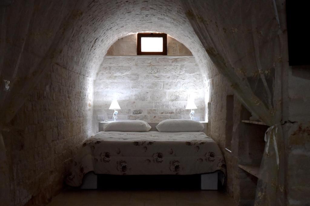 ein Schlafzimmer mit einem Bett in einer Ziegelwand in der Unterkunft Agape fra i Trulli Dimora Ciclamino in Alberobello