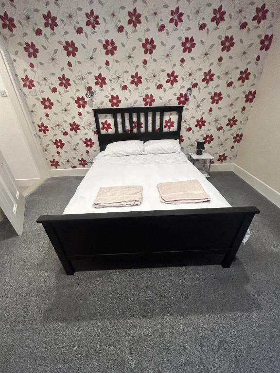 a bed in a bedroom with a floral wallpaper at Canvas House in Carlisle