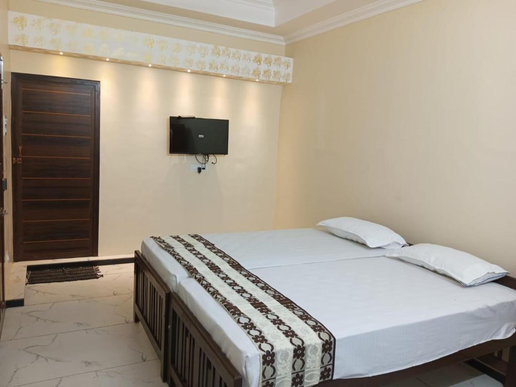 a bedroom with a bed and a tv on the wall at SRI PADMANABHA TOURIST HOME in Chacka