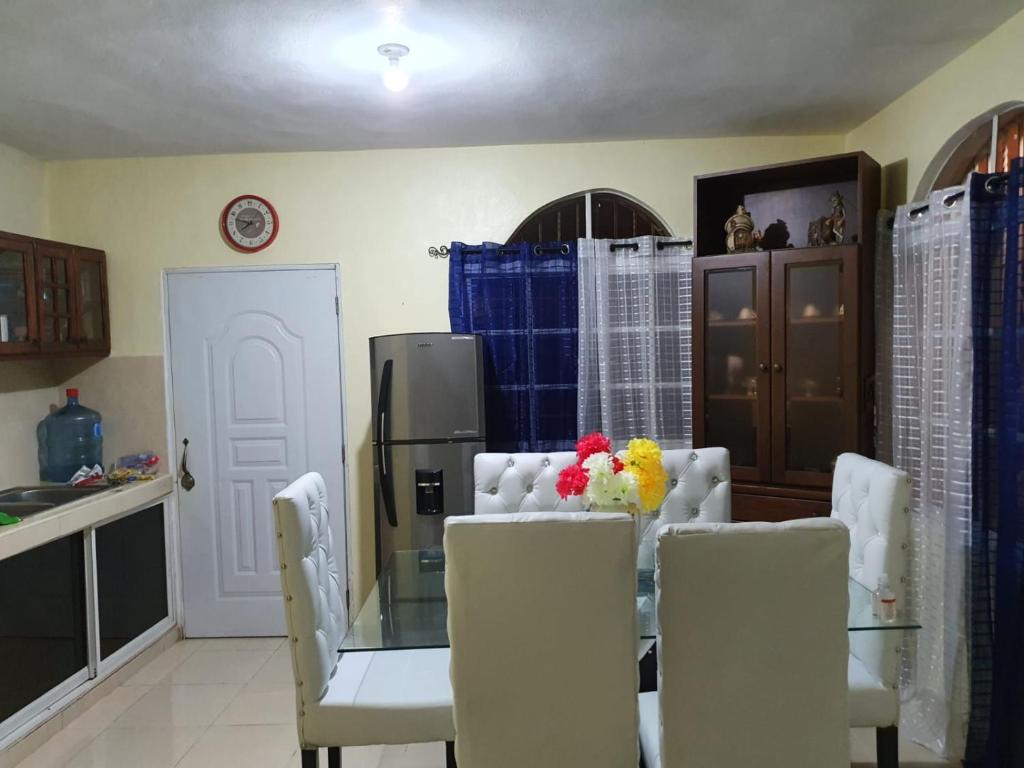 uma sala de jantar com uma mesa de vidro e cadeiras brancas em Casa para la familia em Boca Chica