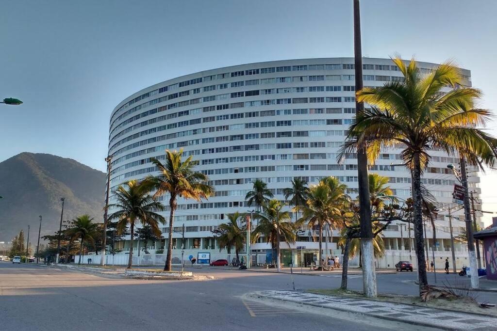 a large building with palm trees in front of it at Apartamento em Peruíbe (Centro) in Peruíbe