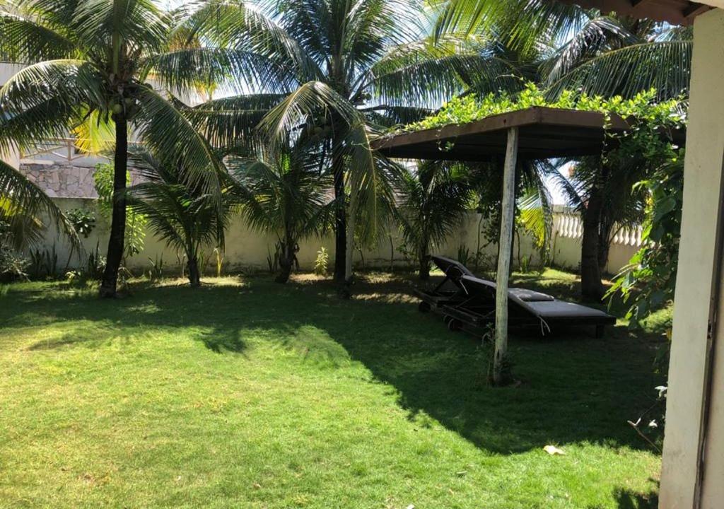 une arrière-cour avec des palmiers et un banc sous un pavillon dans l'établissement Casa de praia, à Caucaia