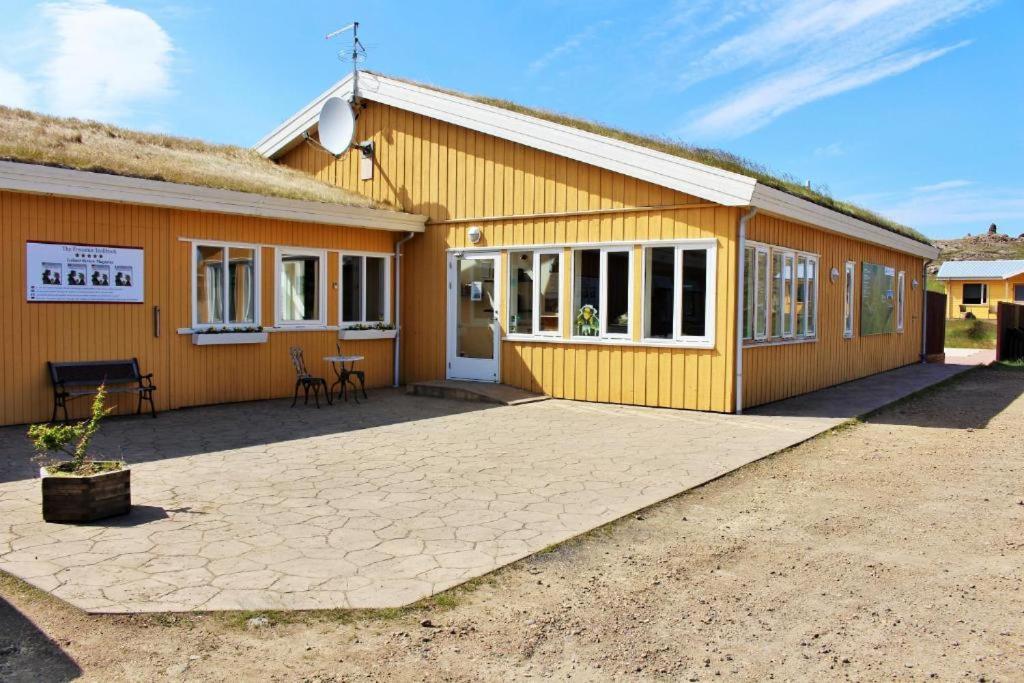 a yellow building with a patio in front of it at Fossatun Camping Pods & Cottages - Sleeping Bag Accommodation in Fossatún