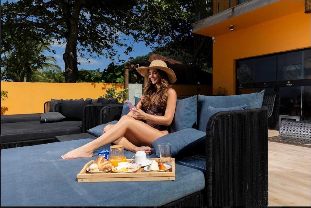 a woman sitting on a couch with a tray of food at Casatua Pousada in Juquei
