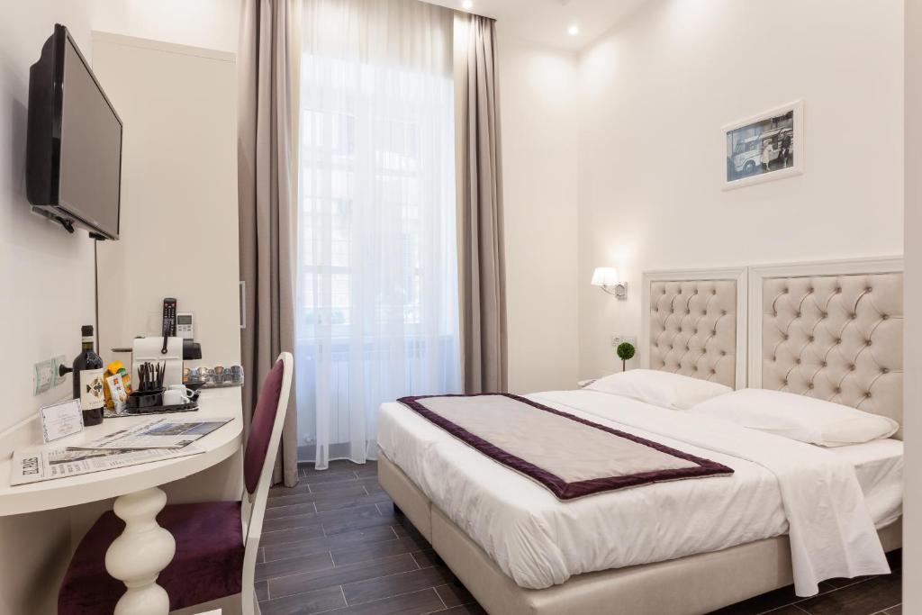 a white bedroom with a bed and a desk and a television at Relais Monti in Rome