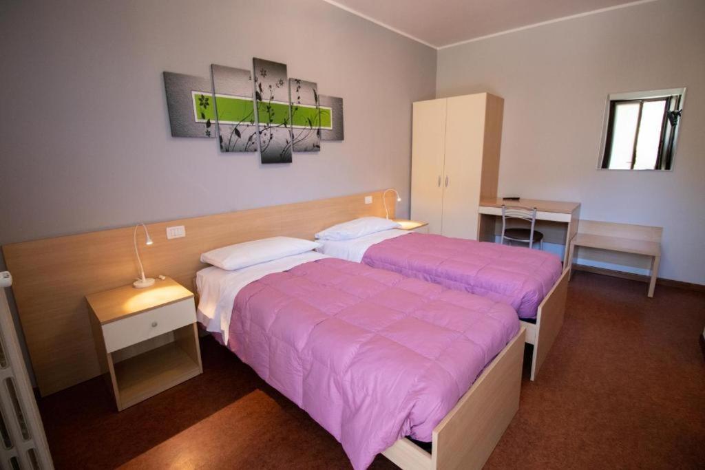 Hotel del Boschetto في Poggiridenti: سريرين في غرفة نوم مع ملاءات وردية