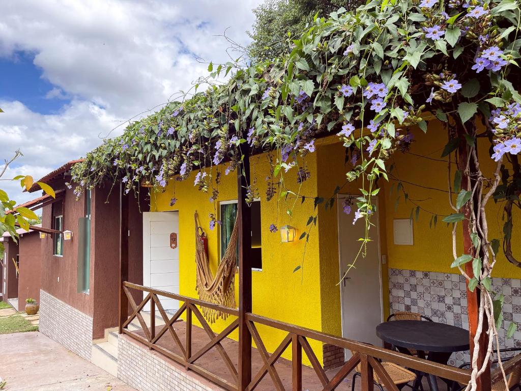 una casa amarilla con flores púrpuras creciendo en ella en Muda Hotel en Tianguá