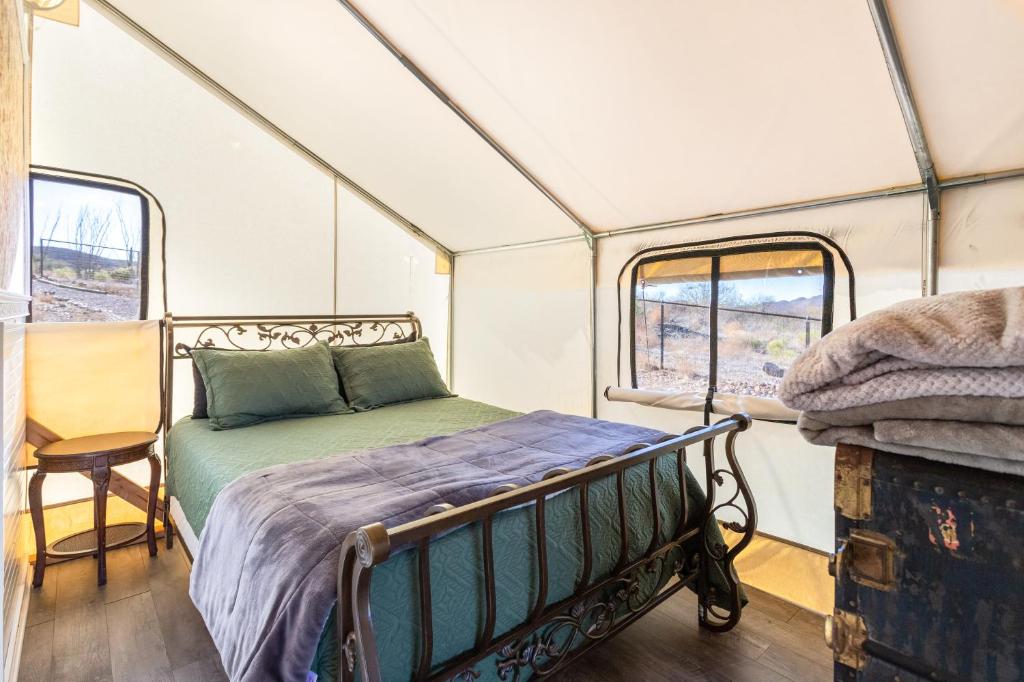 un letto nel centro di una camera con finestre di Silver Spur Homestead Luxury Glamping -The Tombstone a Tombstone