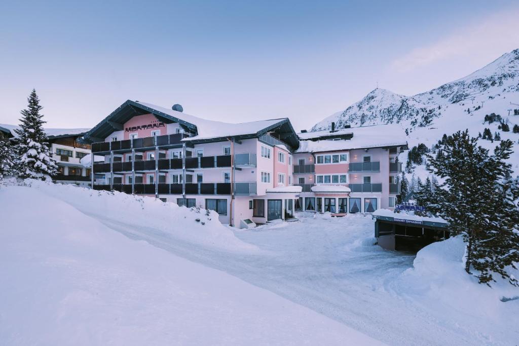 un gran edificio en la nieve con montañas en el fondo en Hotel Montana, en Obertauern