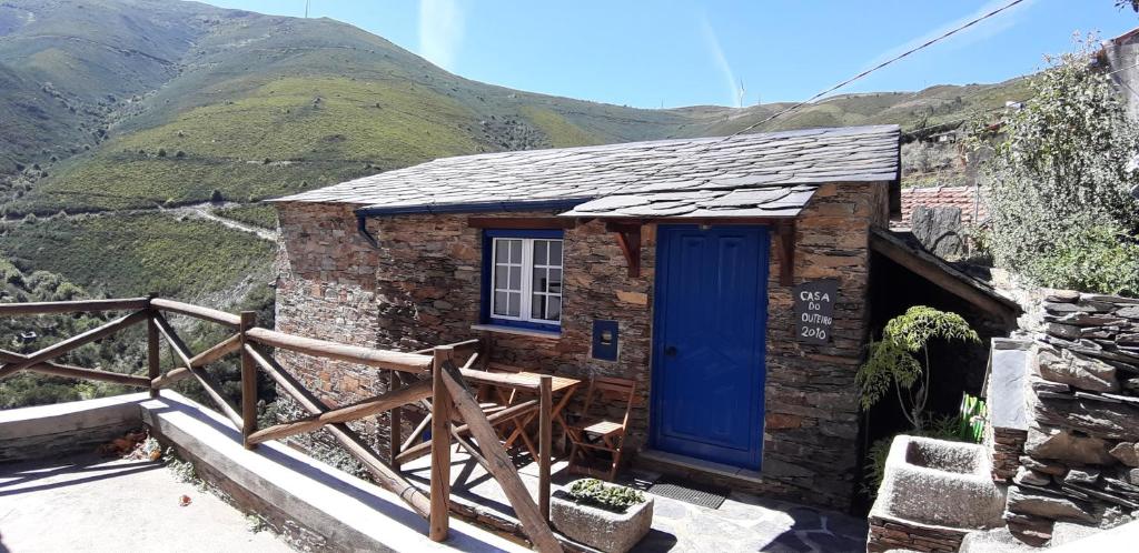 una pequeña casa con una puerta azul en una montaña en Casa do Loureiro en Arganil