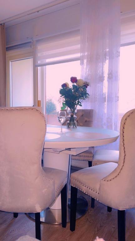 uma mesa de jantar com duas cadeiras e um vaso com flores em Room in Helsinki area em Helsinque