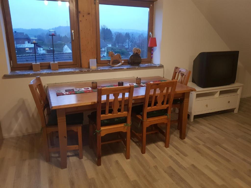 a dining room table with chairs and a television at Ferienwohnung auf kleinem Pferdehof in Much in Much