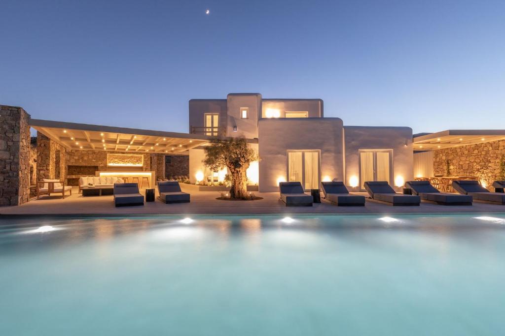 un complexe avec une piscine ouverte la nuit dans l'établissement Blue Eye Grand Villa Mykonos, à Kalafatis
