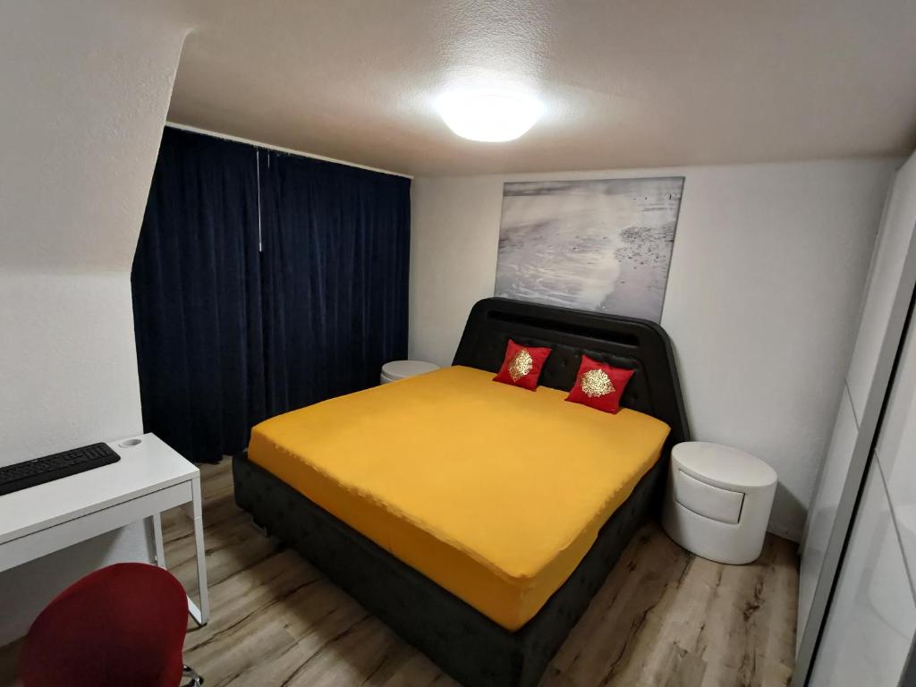 a small bedroom with a yellow bed with red pillows at Butthouse Apartments in Trimbach