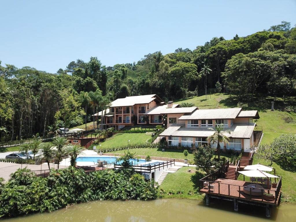 una casa en una colina junto a un cuerpo de agua en Village Du Lac Hotel, en Pomerode